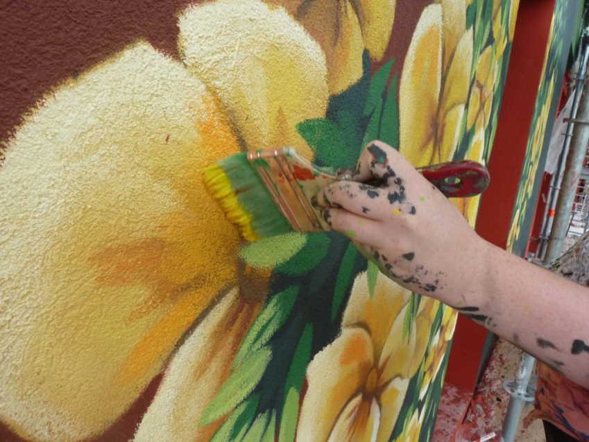 Photographie d'un individu en train de peindre un mur.